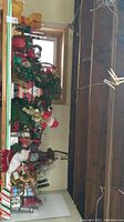 Wide view of shelf showing multiple Christmas decorations including wreaths, figurines and stands.