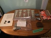 Collection of Canadian coins in protective sleeves, loose coins in bag labeled 'Complete 1992-2000 set', a box of match stick book covers, and two lighters on a wooden table.