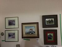 Photo showing all five pieces arranged on a wall, including the white house painting centered, two floral prints on left, dog drawing and horse photo on right.