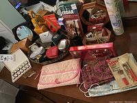 Overview of various items on table including pouches, boxed perfumes, makeup brushes, and decorative pieces