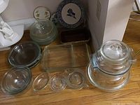 Overview of the lot showing decorative plates arranged behind various clear glass bowls and baking dishes.