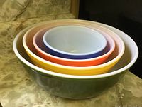 Stacked view of four Pyrex bowls in different colors and sizes.