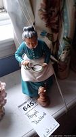Front side of Royal Doulton figurine showing the elderly woman feeding a dog with a bowl and spoon.