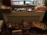 Overview of sewing supplies including thread organized in boxes and trays, scissors, and sewing accessories on a windowsill and shelf below it.