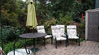 Wide shot of table with umbrella and four chairs on brick patio