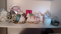 Shelf display of assorted teacups, saucers, sugar bowl and small baskets