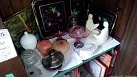 Wide view of trays, candy dishes, Blue Mist jar, and trinket boxes arranged on shelf.