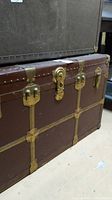 Full view of the brown vintage Langmuir trunk showing metal trim and brass hardware on the corners and edges.