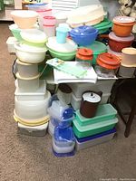 Stacked plastic storage containers of various shapes and colors atop a folding TV tray