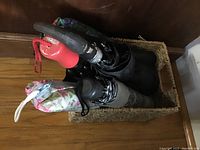 Top view of five small umbrellas upright inside a rectangular woven wicker basket on a wooden floor.