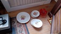 Image showing the full set of plates arranged on the floor along with the red glass candy dish.