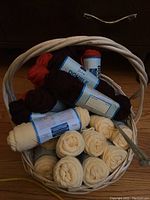 Basket with skeins of cream, dark brown, and orange acrylic yarn, showing full basket contents.