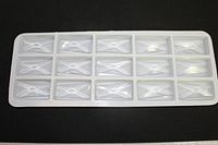 Tray containing 15 Swarovski lead crystal prisms arranged in a 3 by 5 layout, each prism rectangular and clear with faceted surfaces.