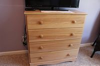 Front view of maple chest of drawers with 4 drawers and round wooden knobs.