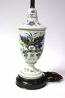 Front side view of the porcelain urn lamp showing detailed hand painted blue floral artwork, dark round base, and power cord.