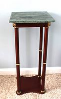 Front view of the marbled top plant stand showing the cherry wood pedestal, gold-tone accents, and marbled surface.