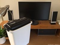 ASUS 24-inch computer monitor and Sylvania paper shredder on wooden desk.