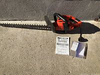 Photo showing entire Black & Decker Hedge Hog hedge trimmer with 24 inch blade, instruction manual and paperwork on concrete surface.