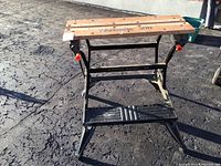 Front view of Black & Decker Workmate 300 work bench with wooden top and black metal frame with orange knobs.