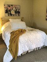 Full view of double brass headboard with bed made with white bedding and beige throw.