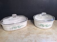 Two Corningware casserole dishes with Callaway Ivy pattern and glass lids shown side by side on a countertop.