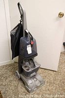 Side view of Hoover Turbo Scrub carpet cleaner with water tanks and body in gray plastic, showing wheels and handle.