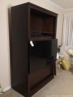 Frontal side view of the TV mounted on the tall wooden cabinet