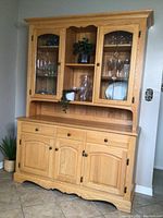 Front view of two-piece solid light oak china cabinet with leaded glass doors and wood panel lower section