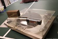 Overview of turntable with dust cover closed and three cleaning tools placed on top (Discwasher wooden box, Discus plastic cleaner, Decca brush)