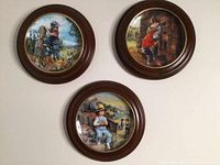 Three Stewart Sherwood collectible decorative plates displayed on a wall, showing colorful scenes of children. Plates are round, 8.5 inches, housed in dark wood frames approximately 11.25 inches diameter.