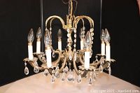 Frontal view of assembled chandelier showing eight arms, bulbs, and hanging crystal prisms.