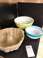Photo showing set of three items: large yellow Pyrex bowl, smaller turquoise banded Pyrex bowl, and beige Pampered Chef fluted bundt pan.