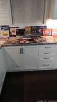 Photo of over 25 children's Christmas-themed storybooks arranged on a counter, showcasing a variety of colorful illustrated covers.