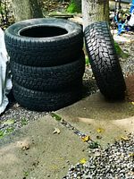 Stack of four Cooper Evolution snow tires on ground next to one leaning tire