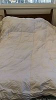 Full view of white quilted duvet spread on bed showing size and texture.