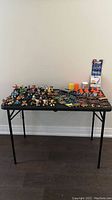 Full lot shown with over 30 Tech Deck Dudes figures displayed with magnetized skateboards, multiple mini skateboards laid out, and several skatepark components on a table.