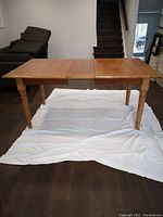 View of the maple dining table with leaf partially extended, showing full length and table legs.