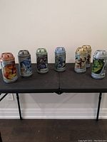 Six original LEGO Bionicle canister containers displayed in a row, showing variety of colors and character artwork, front and center view of all containers.