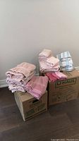 Overview showing stacks of pink towels, both folded face cloths and larger bath towels, along with a separate stack of blue and white striped towels.