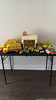 Photo showing entire set on table including schoolhouse, three buses, playground toys, figures, and furnishings.