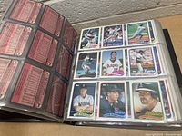 Photo showing card fronts featuring multiple baseball players from different teams in 1989 Topps design inside plastic sleeves in binder.