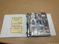 Open binder with two certificates visible on left and nine cards on right page