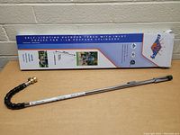 Flame King outdoor propane torch and its original packaging box, showing the flexible inlet hose with brass fitting and long metal torch shaft.