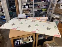 Full view of unfolded fold-up soft baby play pad on table showing animal prints and fold lines.