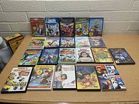 Front view of 24 kids DVDs arranged in rows on a table. Titles and covers clearly visible.
