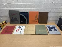 Photo of 9 vintage yearbooks arranged on a table, visible titles include Link 1950, 67 Cardinal, and Antepian 1946.