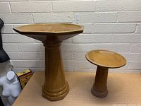 Front view of large and small ceramic bird baths showing their size difference and shape details.