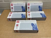 Five boxes of Synguard Nitrile Exam Gloves stacked, showing front of packaging indicating powder free, latex free, size small, 100 gloves per box.
