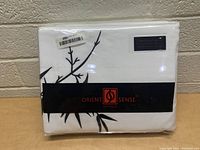 Photo of the folded and packaged white duvet cover set with black bamboo branch design and Orient Sense Australia branding visible.