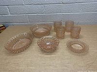 Photo of 7 pieces vintage pink glassware on table including bowls and drinking glasses